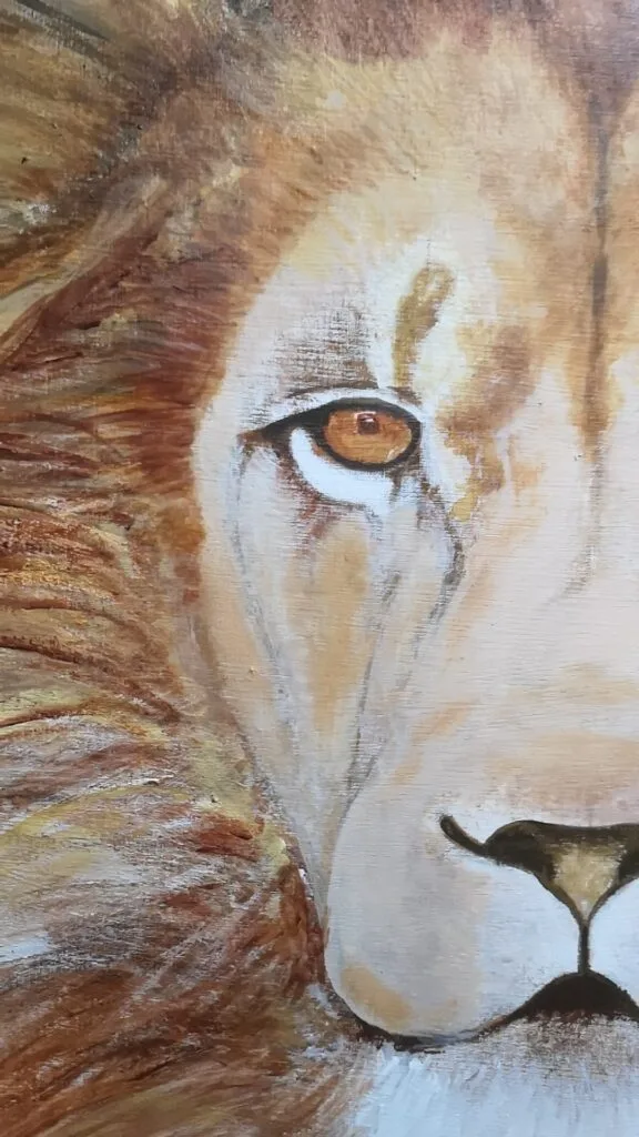 Detalle del ojo de un león pintado a mano con pintura acrílica, mostrando expresividad y profundidad.
