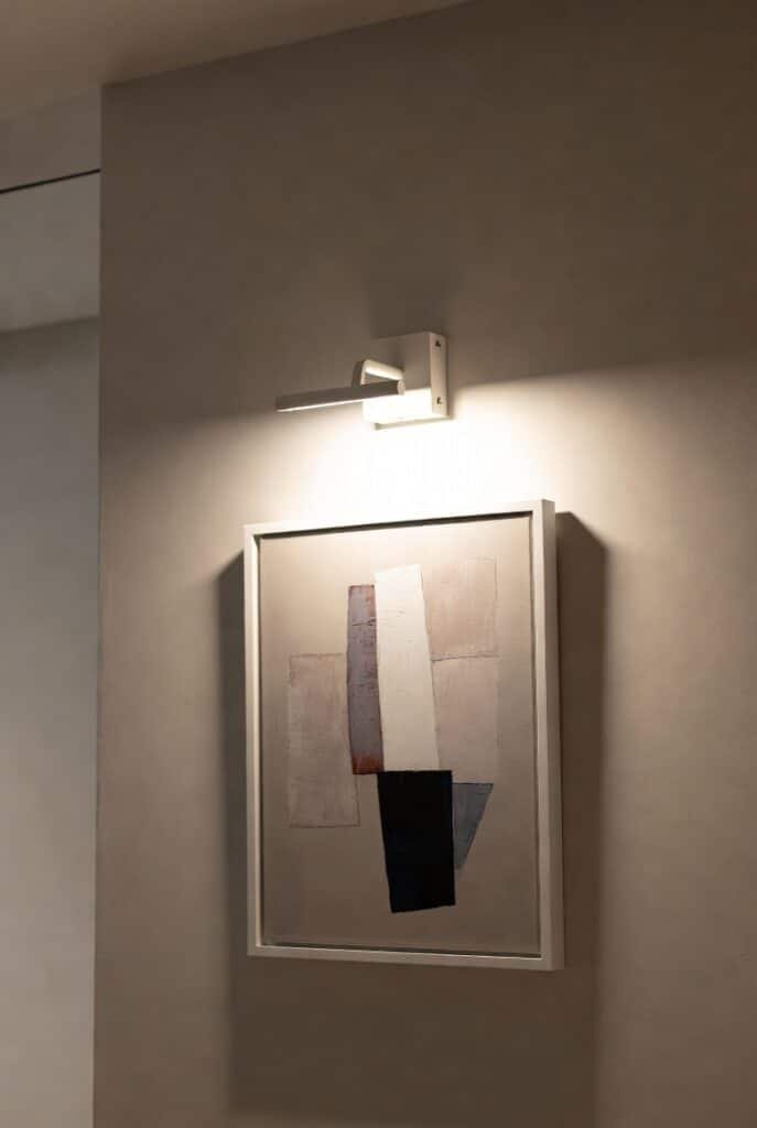 Aplique de pared iluminando cuadro contemporáneo en interior moderno