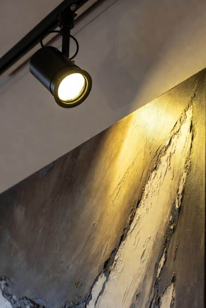 Foco LED orientable iluminando cuadro contemporáneo sin reflejos