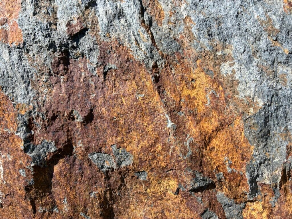 Roca rugosa con manchas de ocre, violeta y gris que sugieren una paleta para pintura abstracta