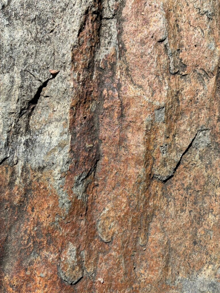 Superficie de roca con vetas ocres, grises y marrones y fisuras verticales